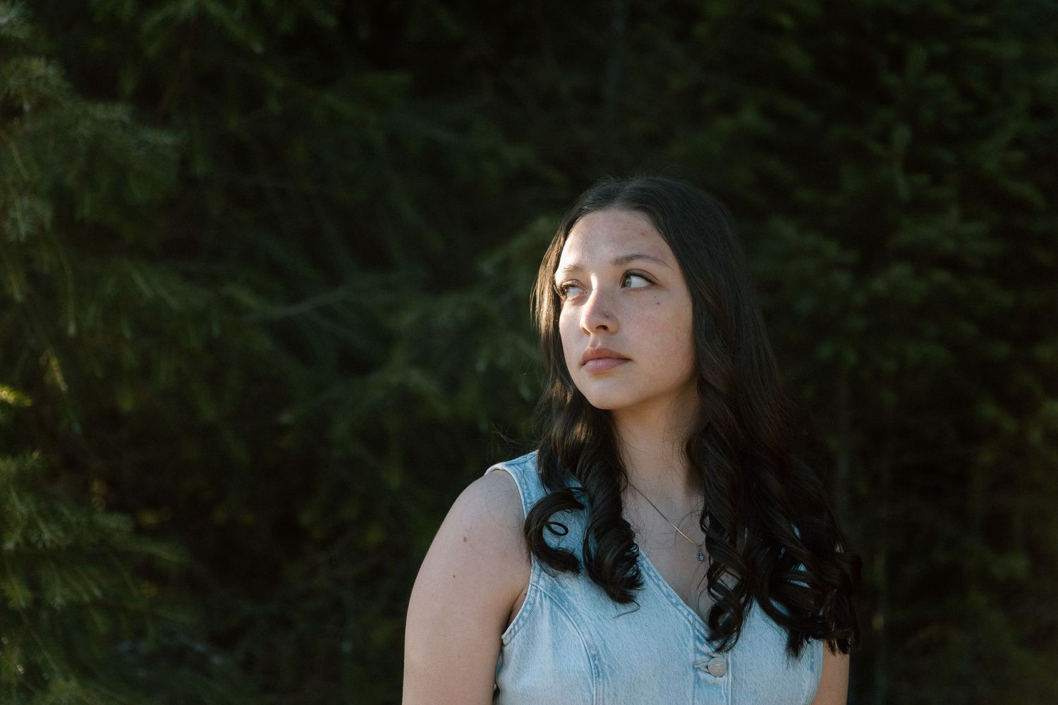 Outdoor portrait with evergreen trees creating natural backdrop.