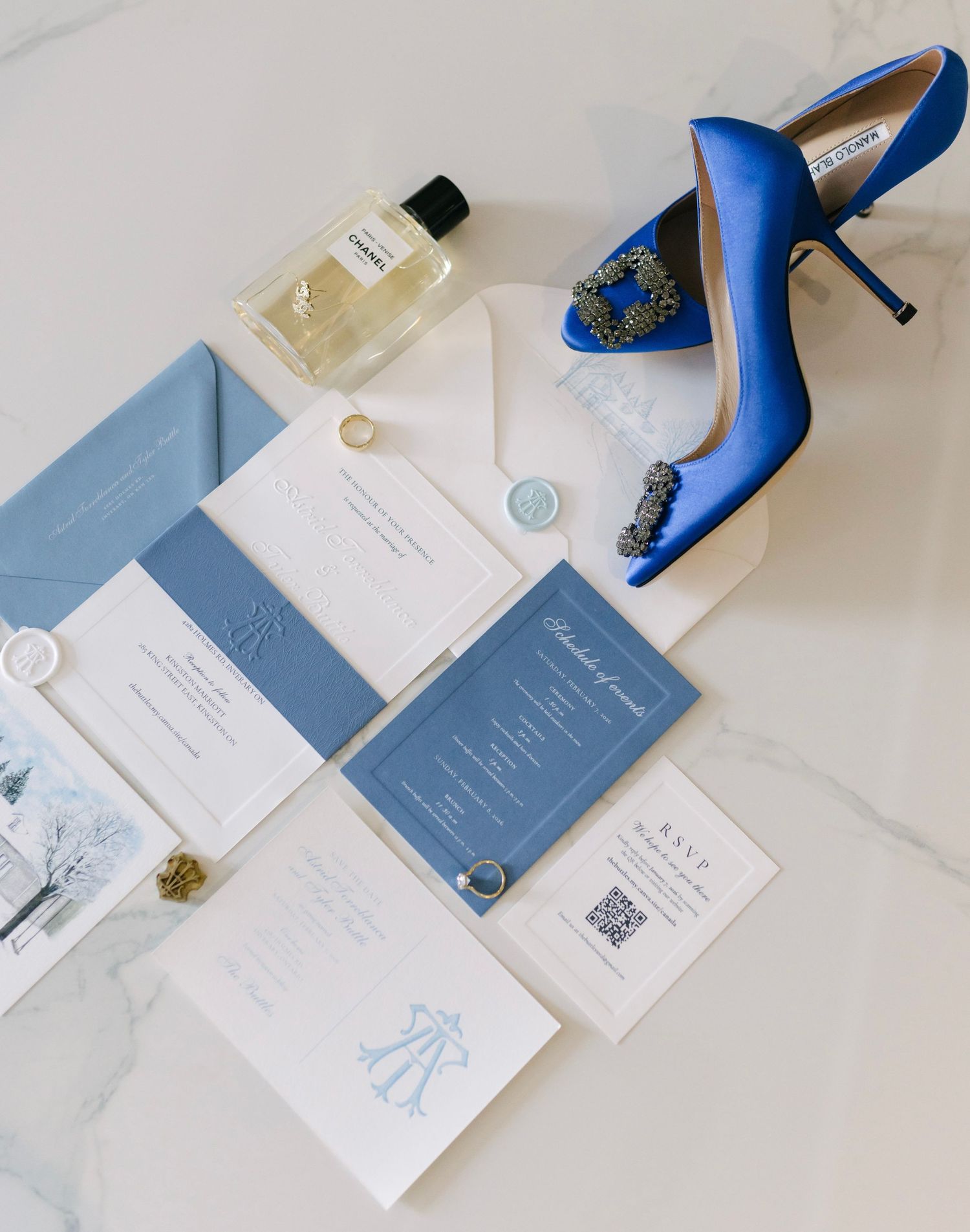 Blue wedding stationery, perfume and heels arranged on marble.