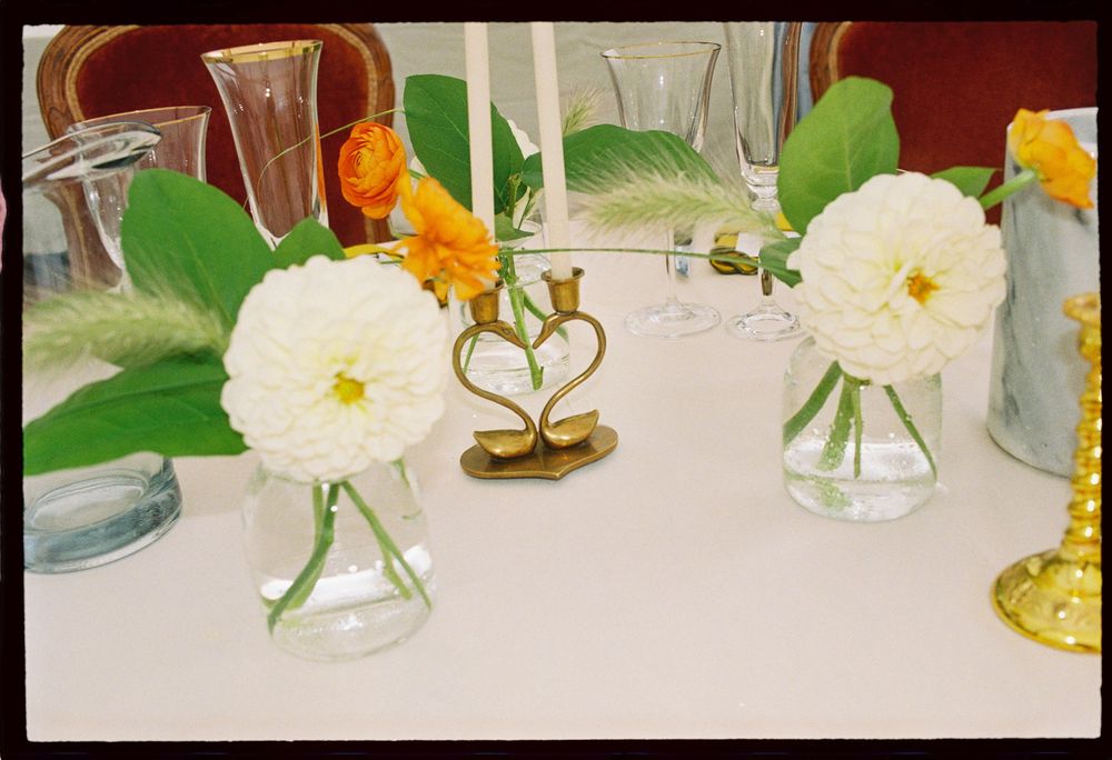 Detail picture of flowers and heart shaped candle holders on the tablescape of a summer wedding reception celebration under a tent in Maine.