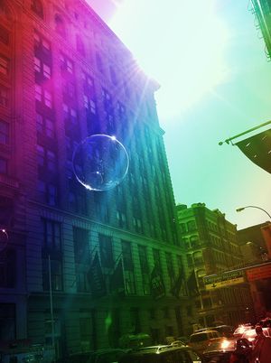 Urban cityscape featuring a brick building facade illuminated by vibrant rainbow colors and lens flare effects.