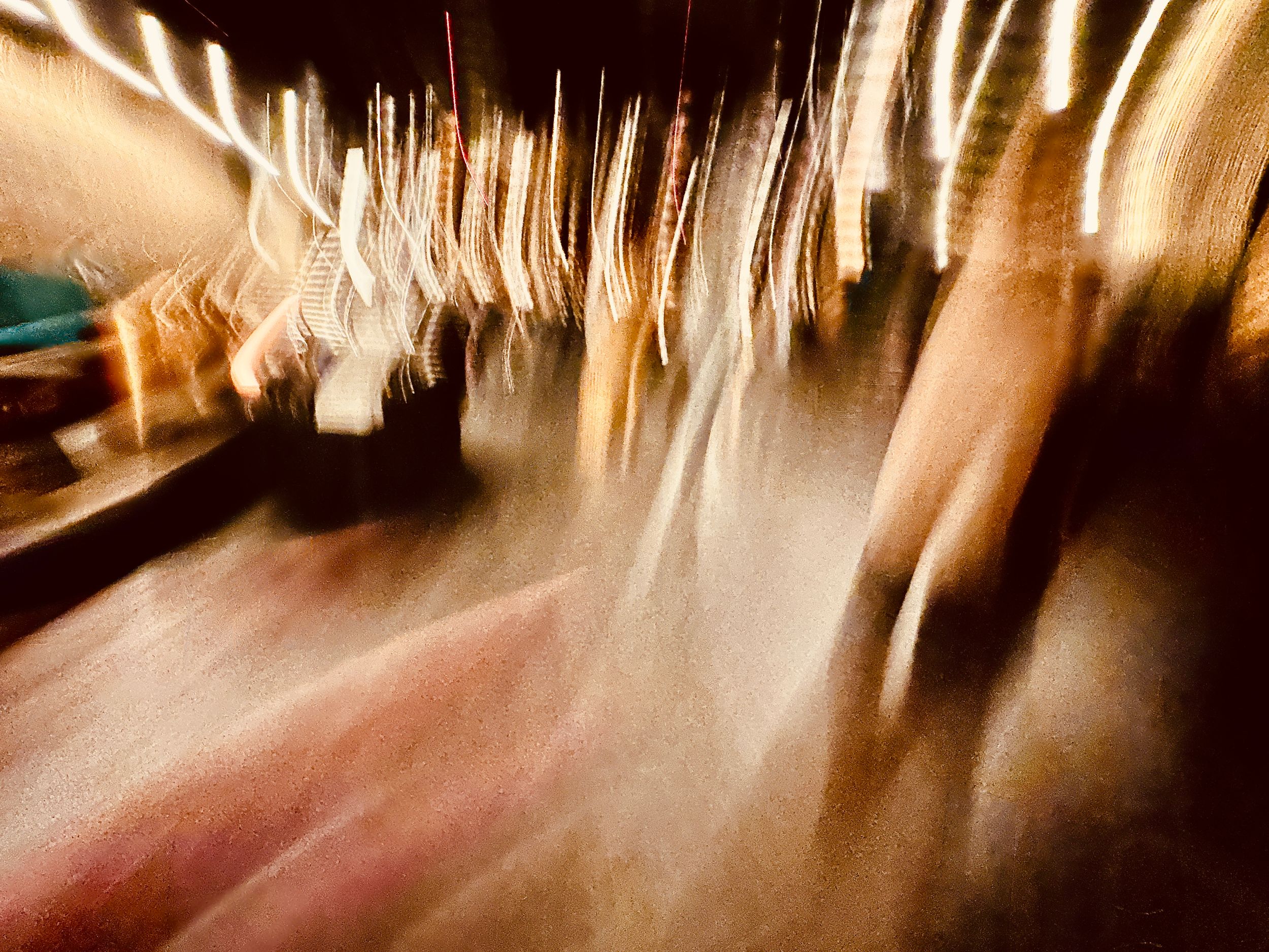 Abstract motion blur photograph showing streaks of light and movement creating a dynamic pattern in beige and brown tones.