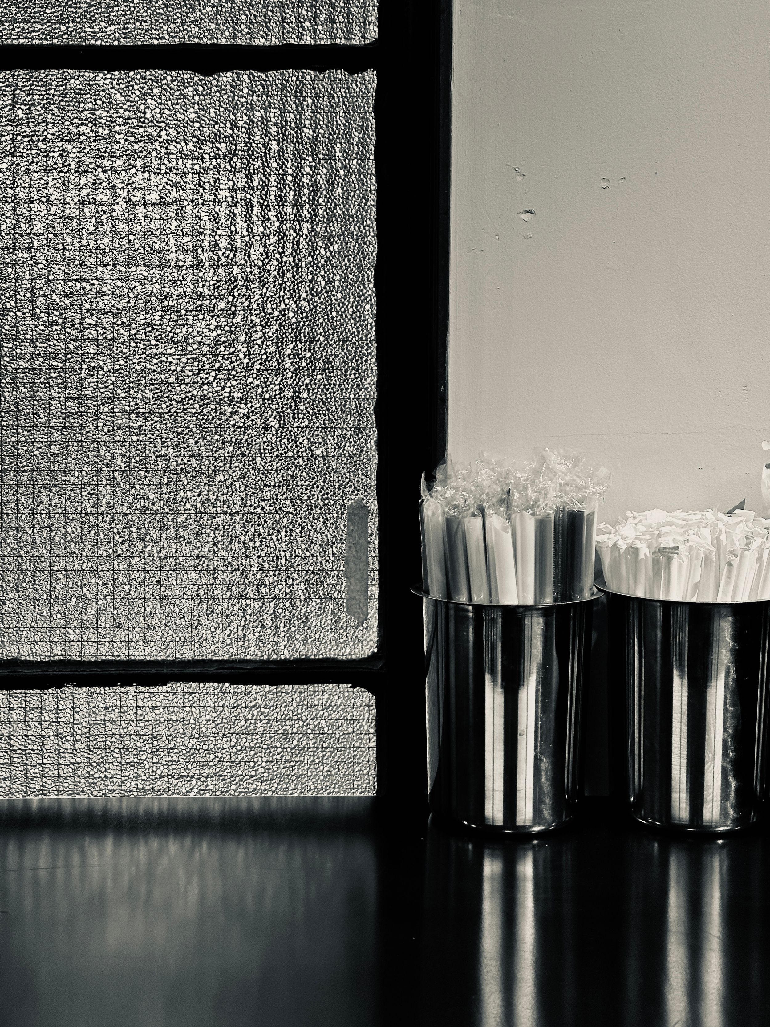 Horizontal black and white abstract pattern with vertical streaks of light reflecting on a dark surface.