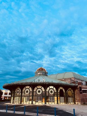 Historic Carousel House pavilion with ornate Victorian architecture and copper domed roof under dramatic blue sky.