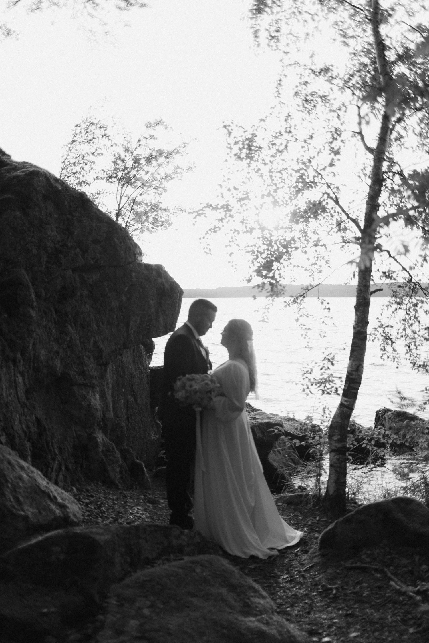 Black and white montage of a romantic couple's silhouettes against scenic cliffs and trees overlooking water.