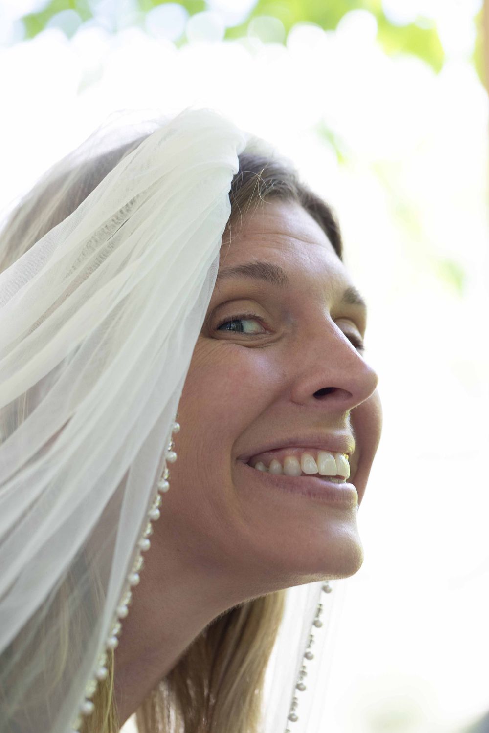 A sequence of four close-up profile shots showing a smiling bride wearing a white veil and earrings.