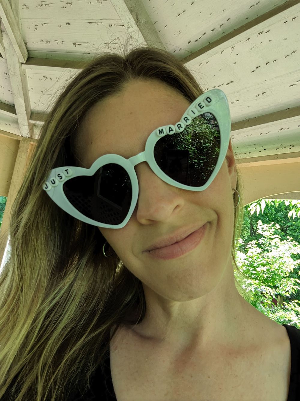 A person wearing mint green cat-eye sunglasses poses in a sequence of five selfie photos outdoors.