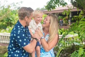 Two people embrace and laugh together while standing in a tropical garden landscape.