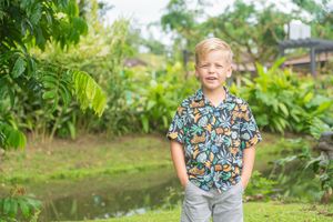 Children wearing colorful tropical shirts and shorts standing together on a sandy path.
