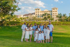 Group photo of people wearing white and blue outfits standing on a grassy lawn with resort buildings in the background.