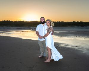 A romantic sunset beach portrait with calm waters and glowing sky in the background.