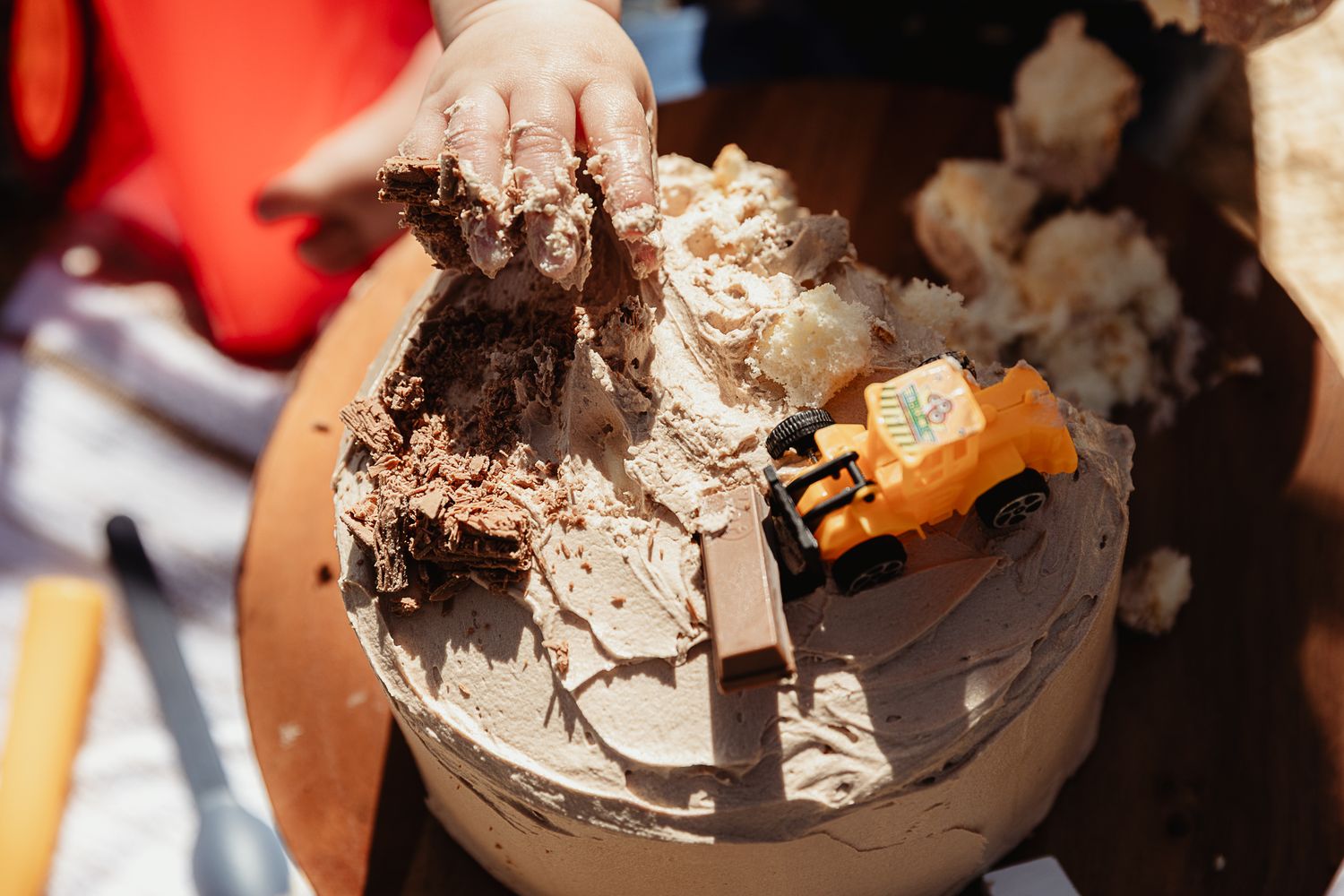Boy getting hands messy with a cake at a construction cake smash photo shoot