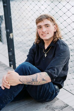 Portrait series against chain link fence showing casual poses and tattoos.