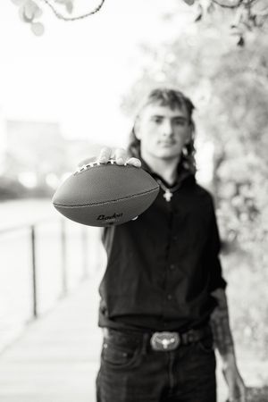 Black and white portrait with football in outdoor setting.