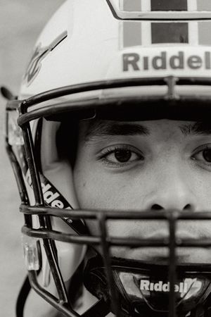 Close-up black and white shot of football player wearing Riddell helmet.