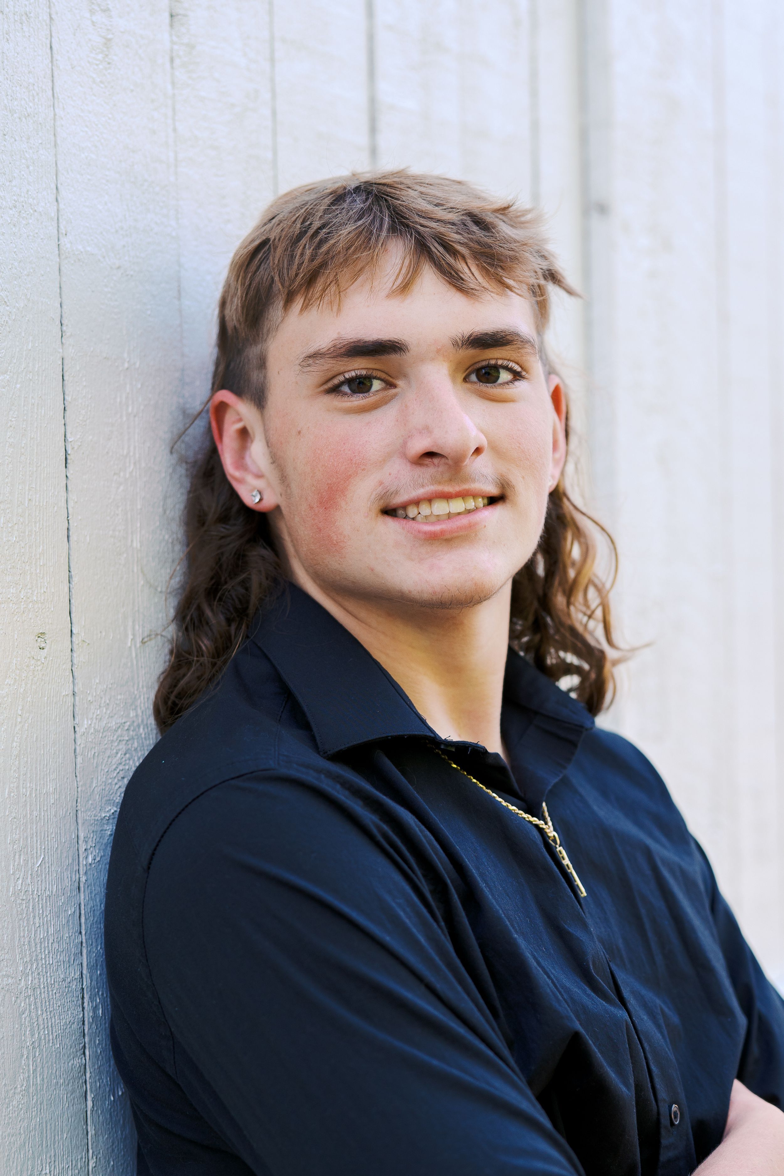 Portrait series against white wall showing casual poses in dark clothing.