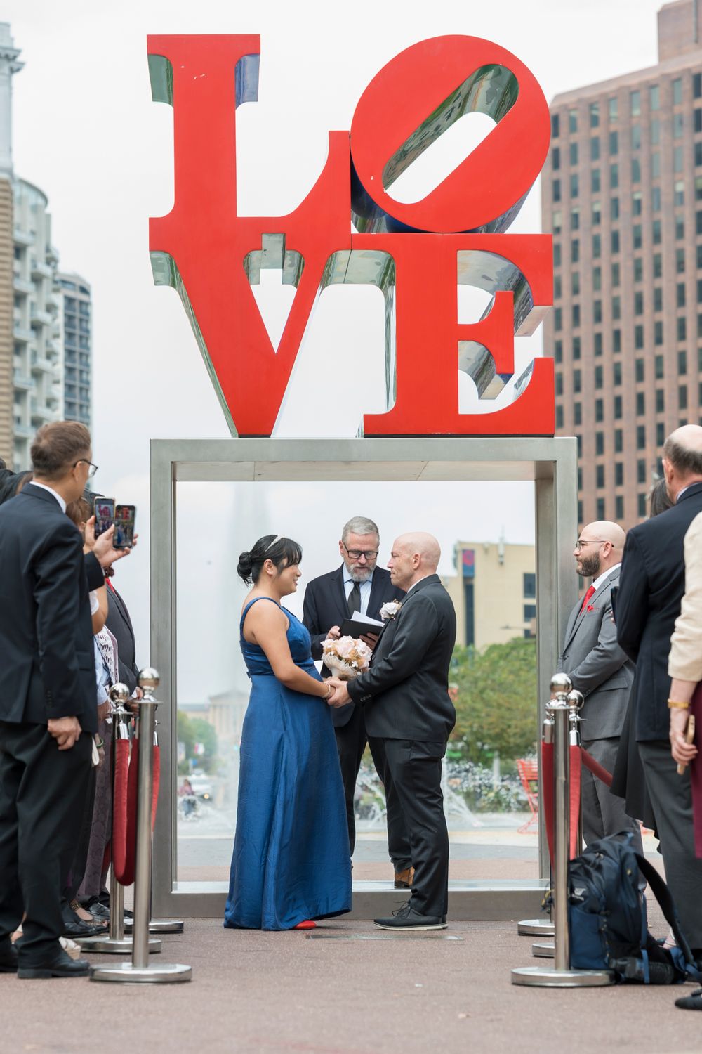 A series of five photos showing a couple posing with the iconic red LOVE sculpture in Philadelphia.