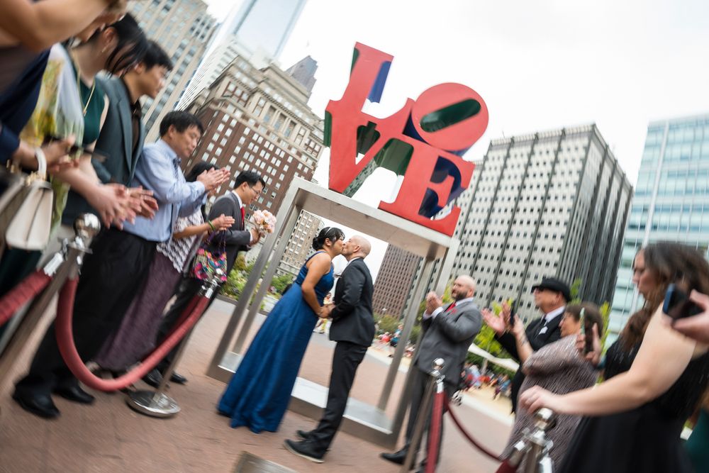 Group of people gathered in front of a building for a public event in an urban setting.