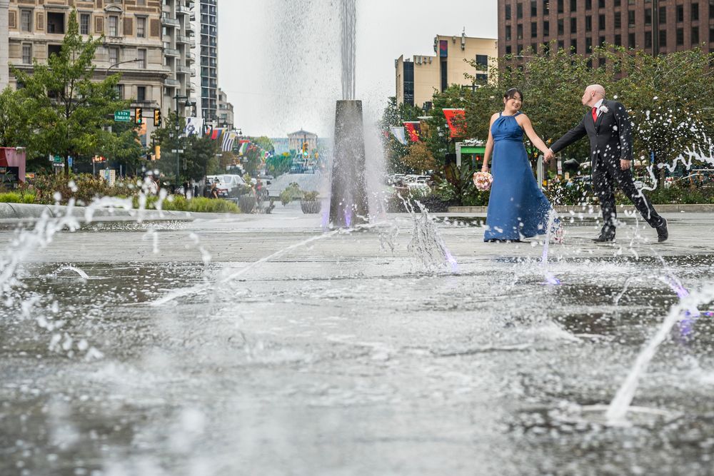 A series of water fountain sprays shooting upward in an urban plaza during daytime.