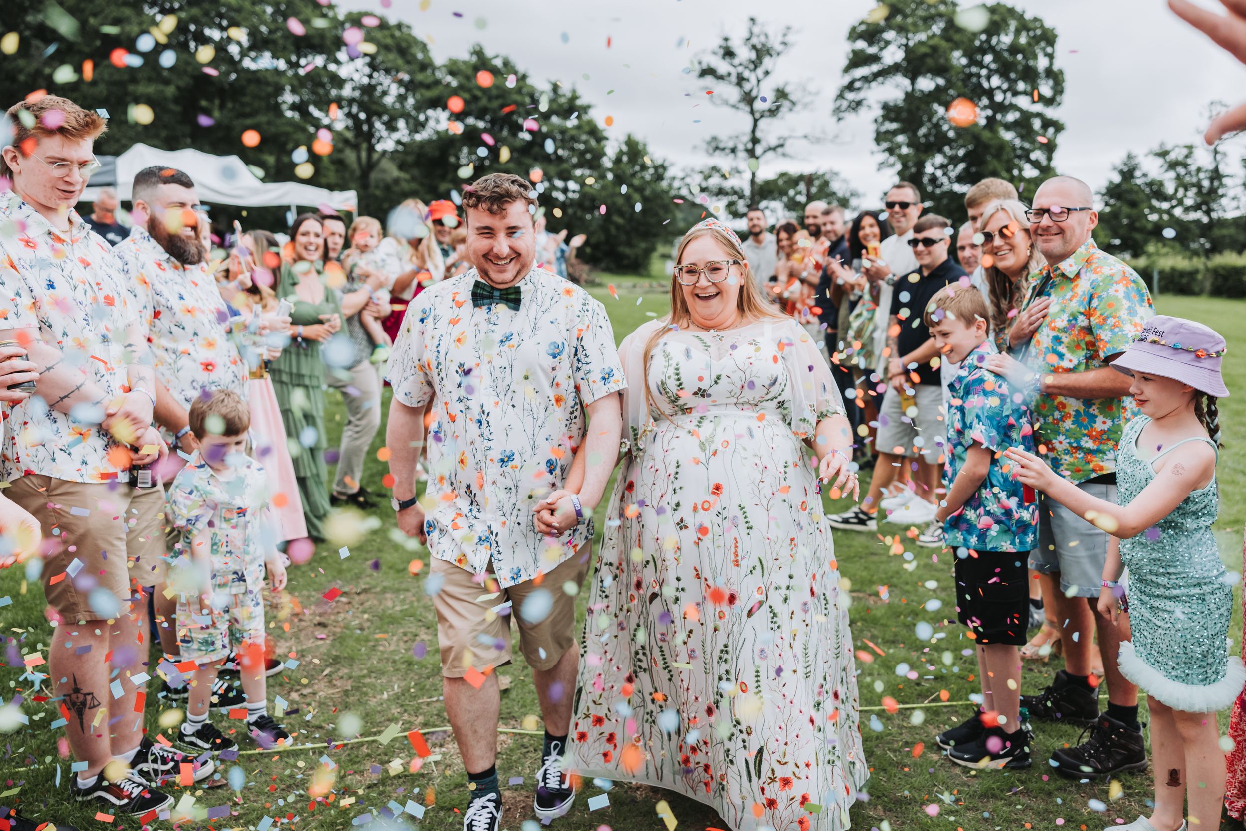 A joyful outdoor celebration with guests throwing colorful confetti in a garden setting.