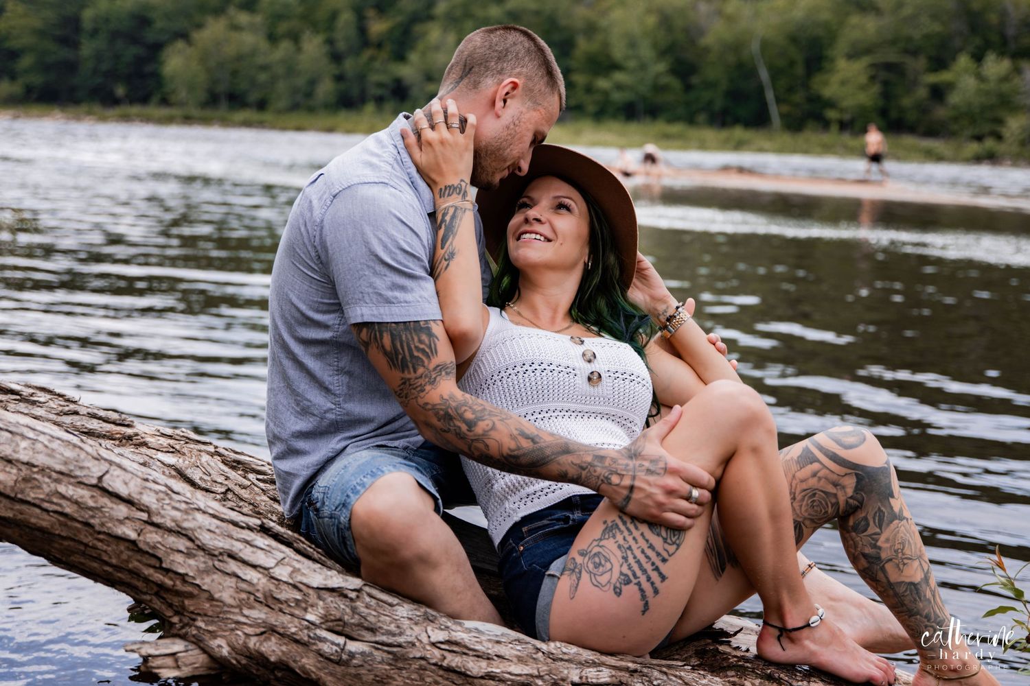 Romantic couple lounging on a fallen log by a lake.
