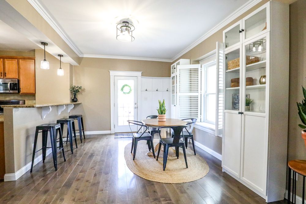Modern open concept living space with hardwood floors, white walls, and track lighting extending down a long hallway.