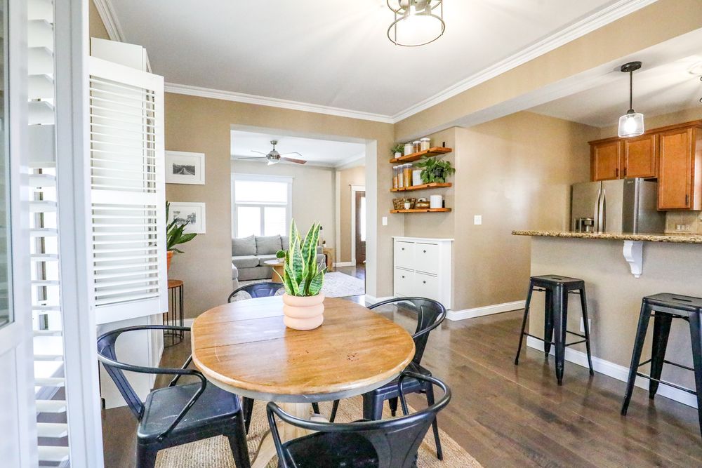 Modern open concept living space with hardwood floors, beige walls, and round dining table near kitchen area.