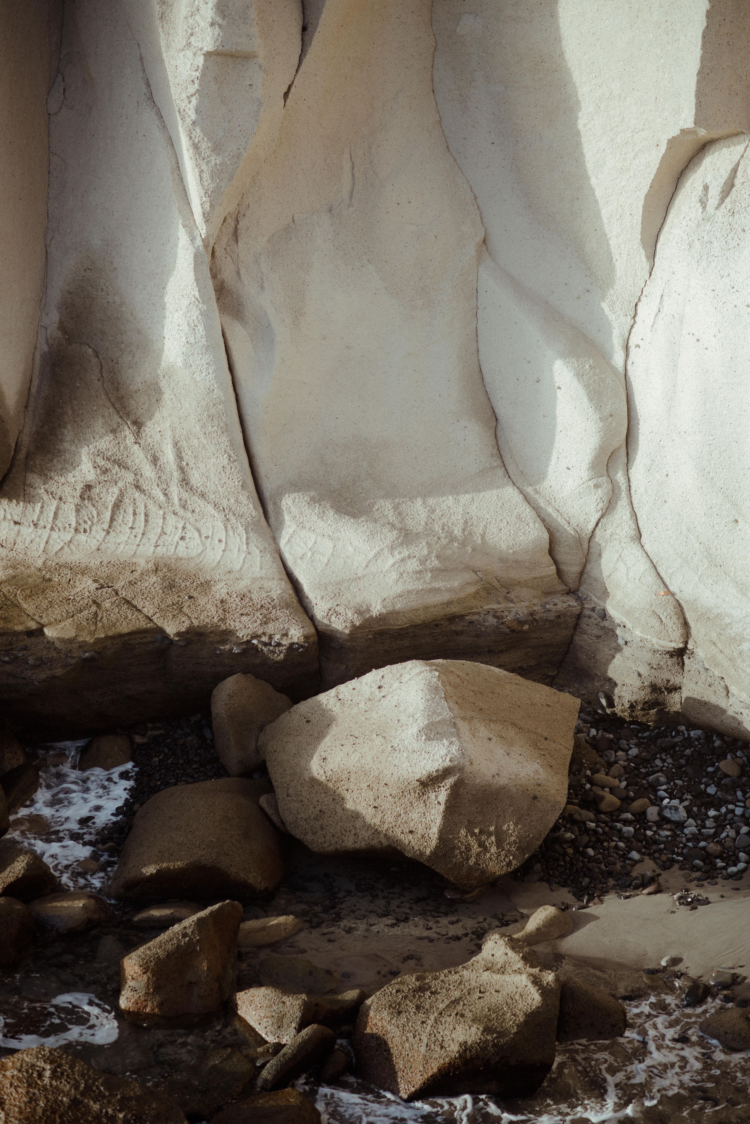 Close-up view of white limestone cave formations with dark water flowing beneath jagged rock surfaces.