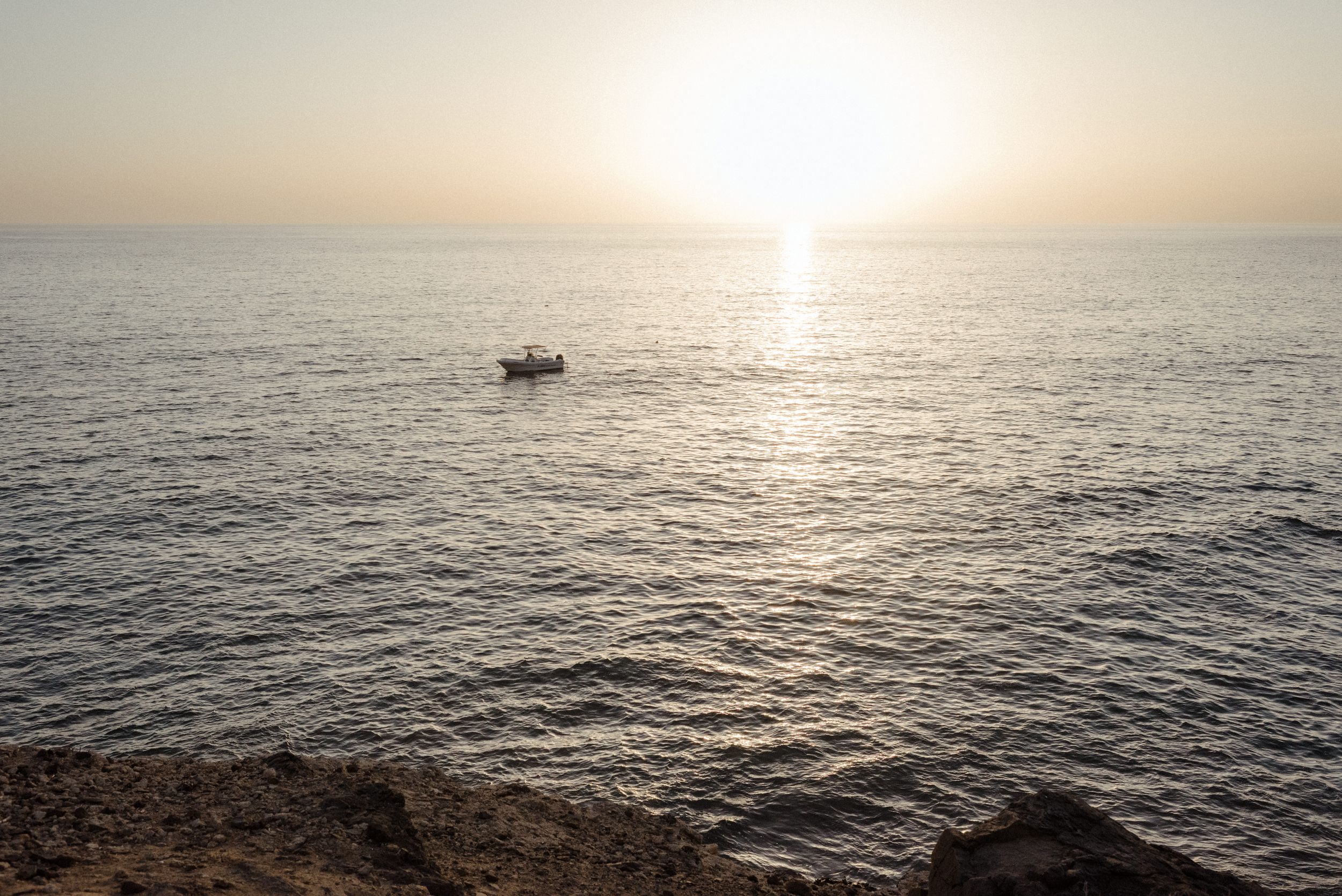 Serene ocean horizon at sunset with gentle waves reflecting golden light across the water's surface.
