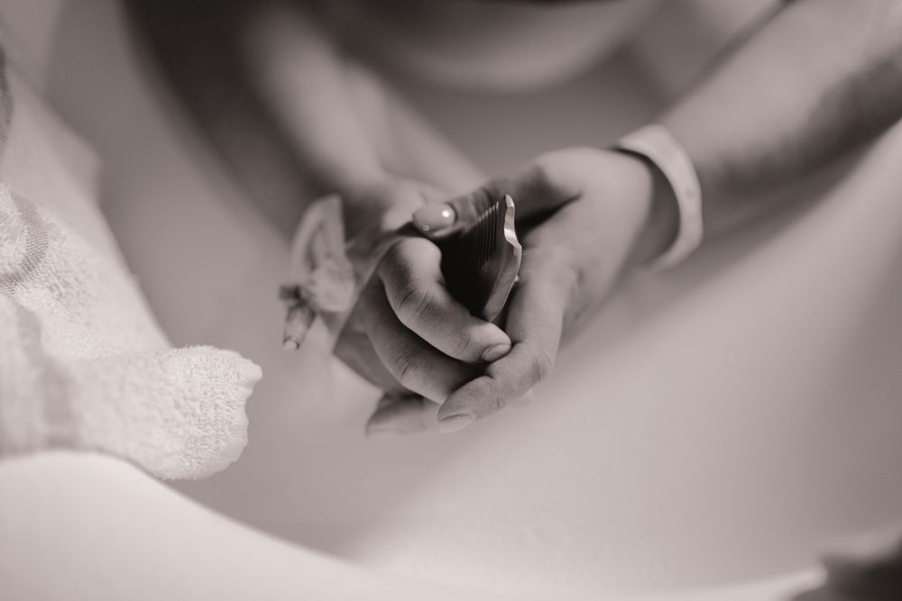 Black and white photo of two hands tenderly clasped together, symbolizing love and connection.