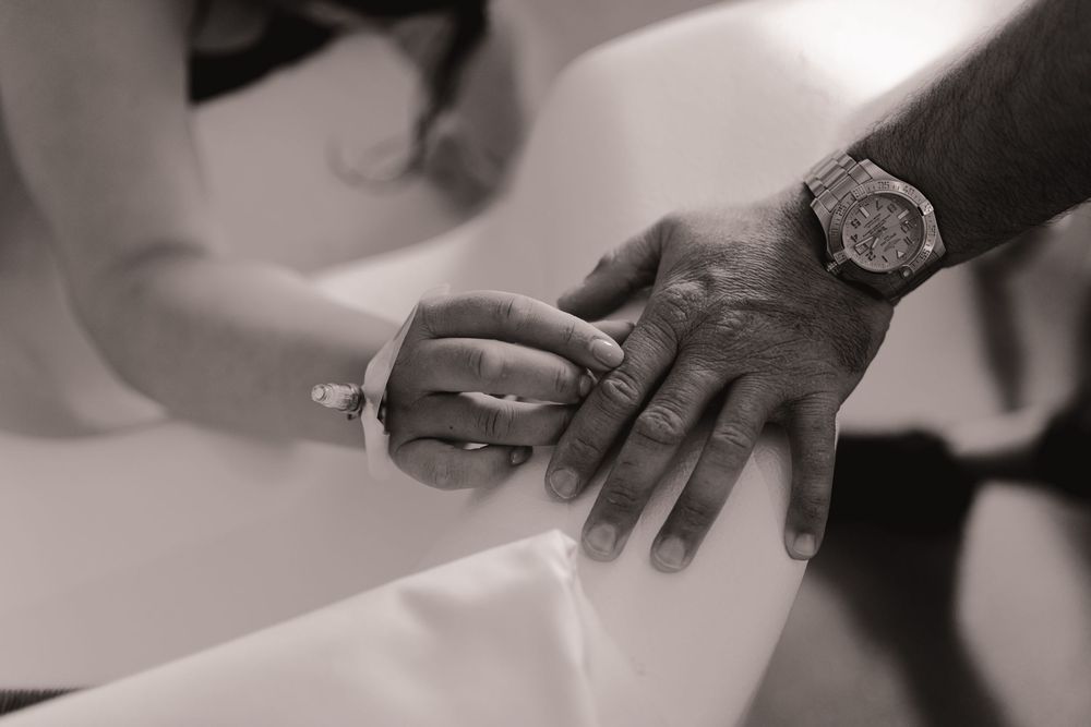 Close-up black and white photo of a couple exchanging wedding rings during a ceremony.