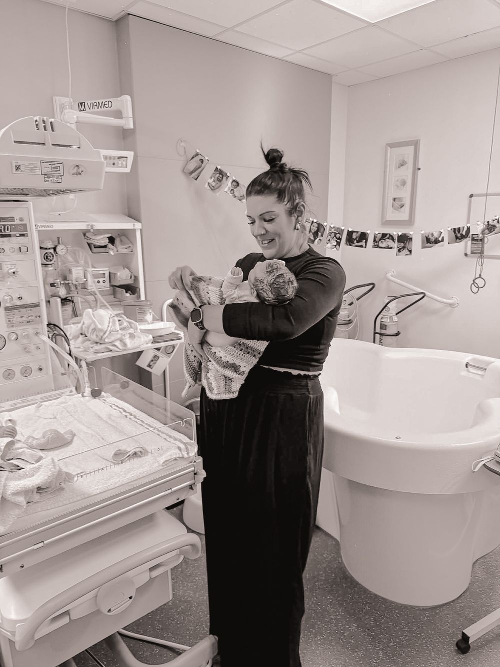 Black and white photo of a mother holding her newborn baby in a hospital maternity room.