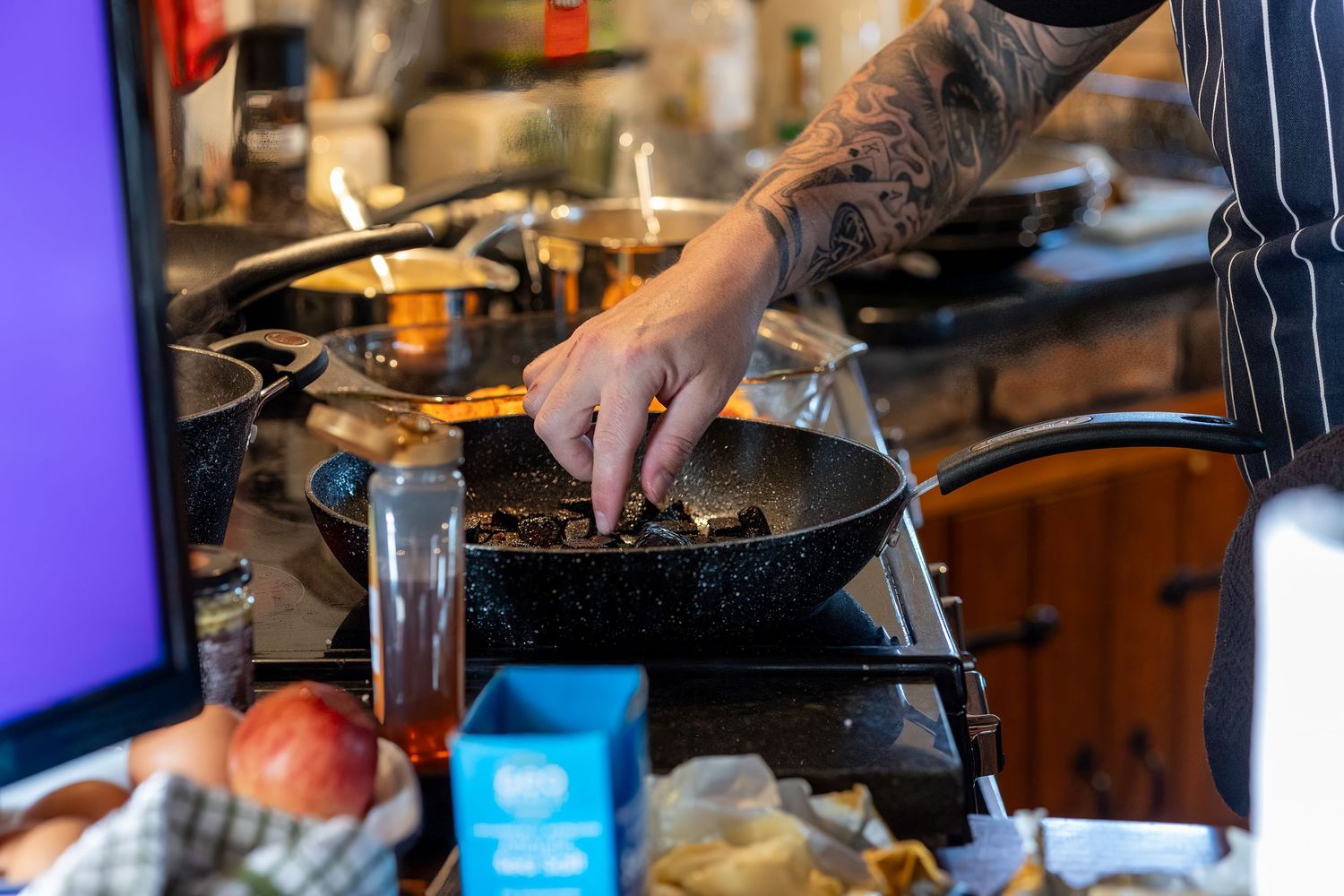 Chef cooking multiple dishes in a rustic kitchen during a private dining wedding at Windmill Farm in Burscough.