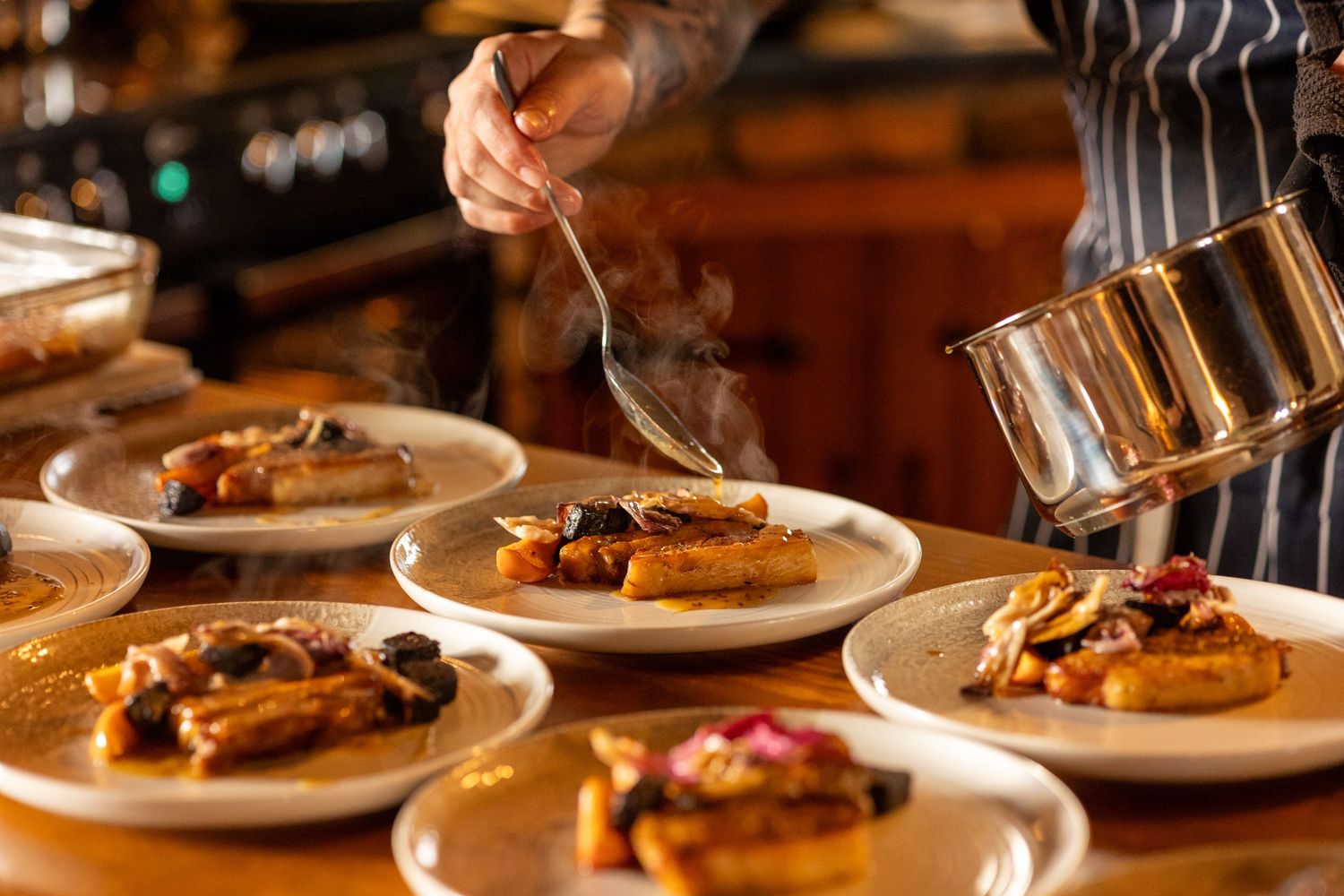Chef pouring sauce over plated dishes, capturing real behind-the-scenes wedding breakfast moments at The Windmill Burscough