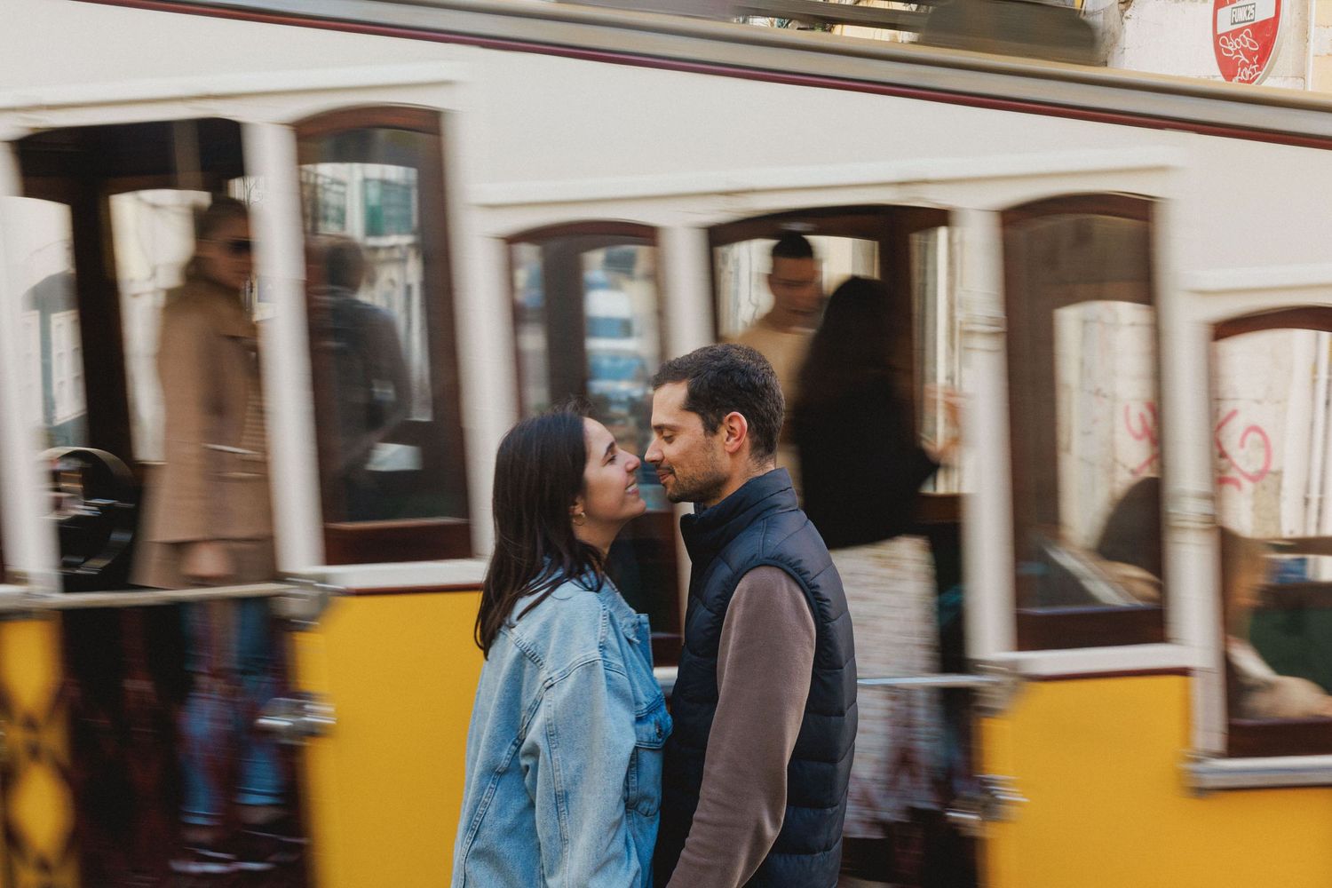 couple portrait is Libon Baixa, where you can see a yellow tram moving through a city street with passengers visible through the windows.