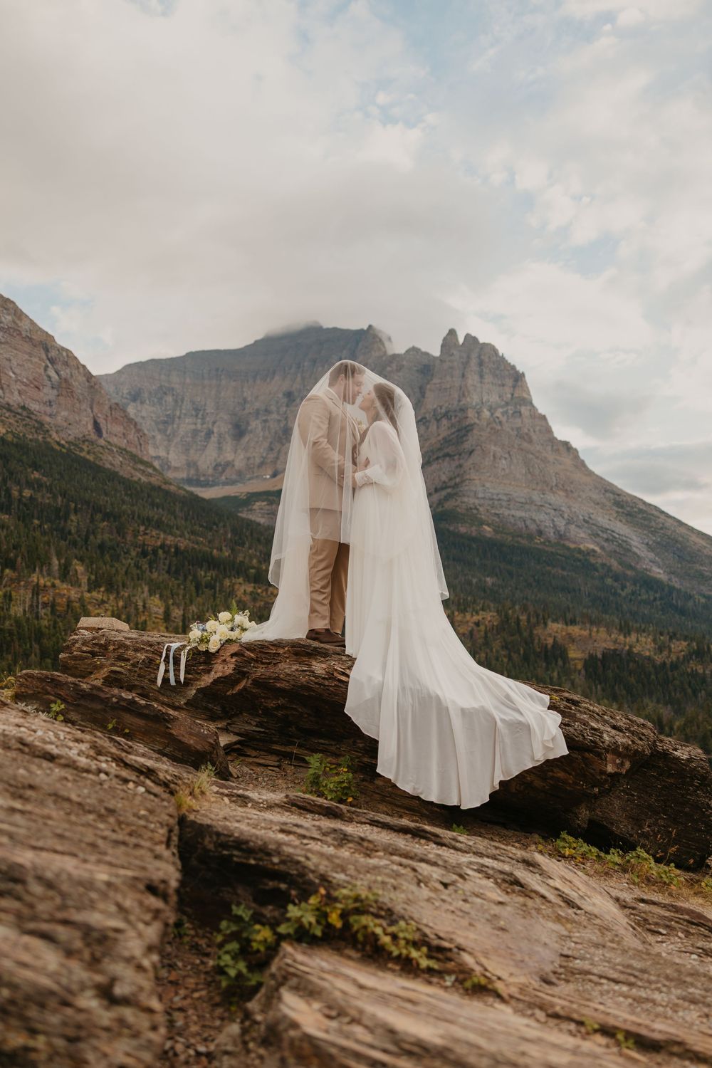 Glacier National Park Eloping Bride and Groom kissing on top of a rock at Sun Point, by local Elopement Photographer Sabrina Marie