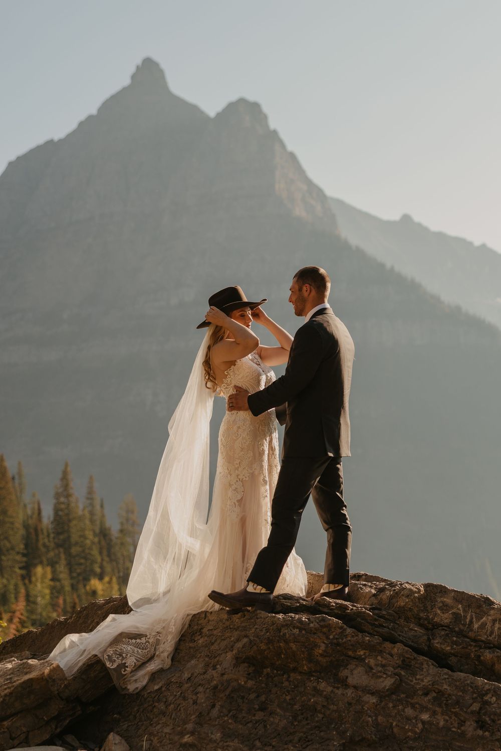 Glacier National Park Eloping bride grabs Grooms cowboy hat and puts it on, captured by local Elopement Photographer Sabrina Marie