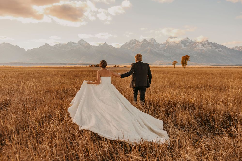 Bride and Groom walking out into the Tetons under the fall sunset captured by a Grand Teton National Park Elopement Photographer