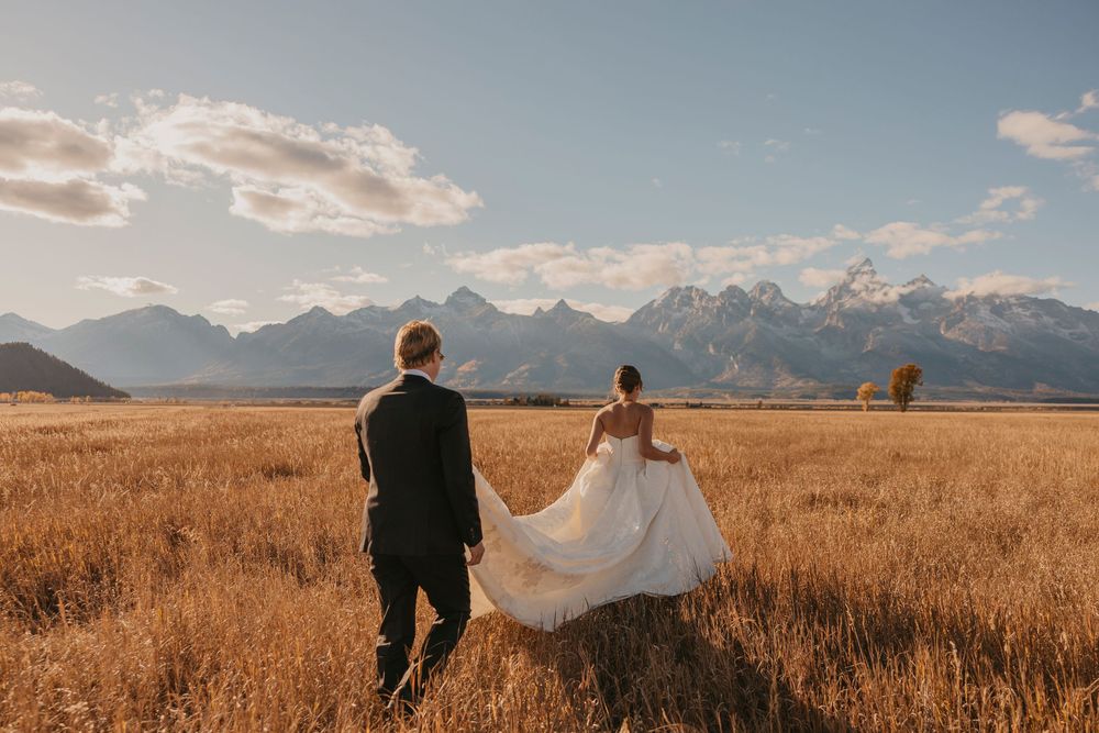 Bride and Groom walking out into the Tetons under the fall sunset captured by a Grand Teton National Park Elopement Photographer