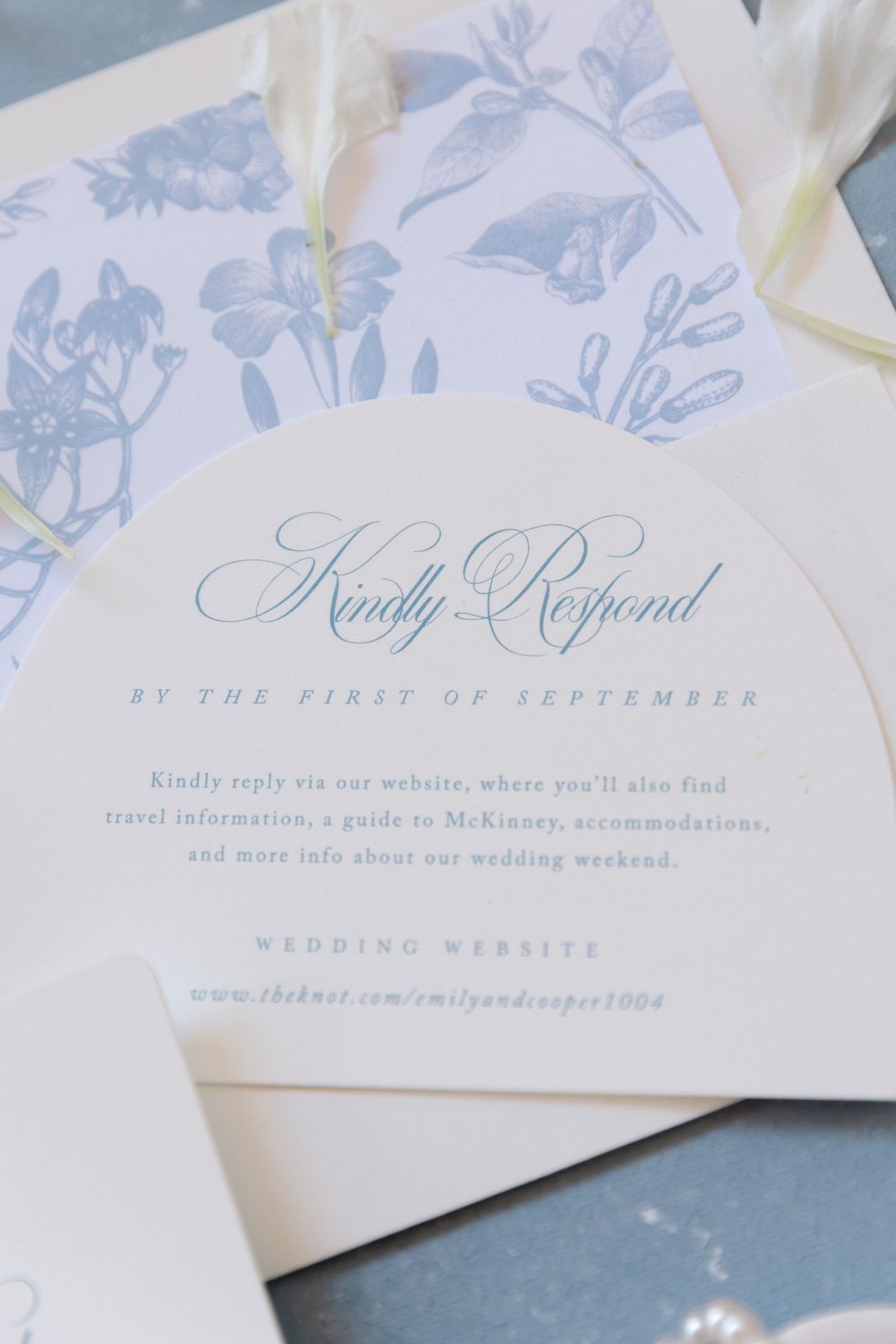 Elegant arched wedding RSVP card with blue botanical print envelope liner and script typography details.