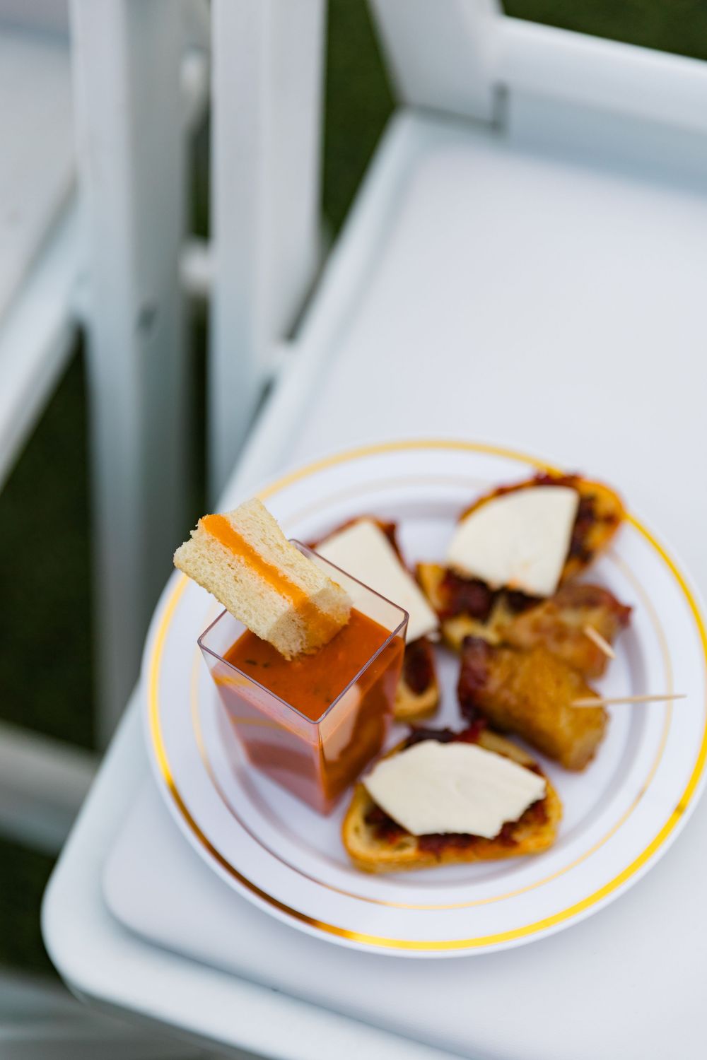 Elegant wedding cocktail hour appetizers served on white chair with tomato soup and crostini.
