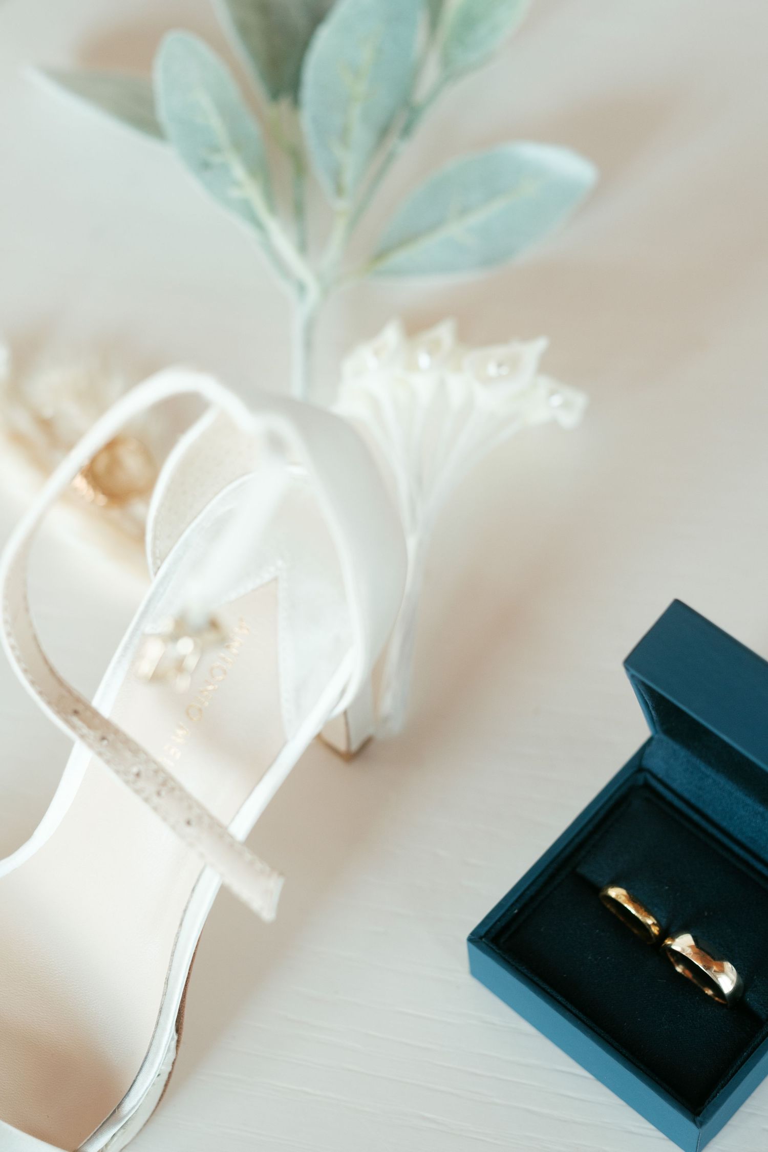 Gold wedding ring displayed in an elegant navy blue jewelry box with soft lighting.