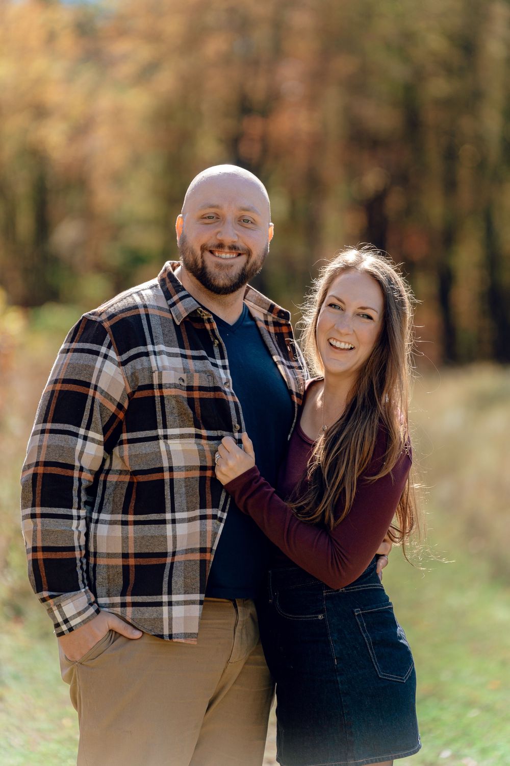 A happy couple poses together outdoors during autumn, wearing plaid and burgundy while embracing Redemption Chapel Trail in Stow, OH for Pic