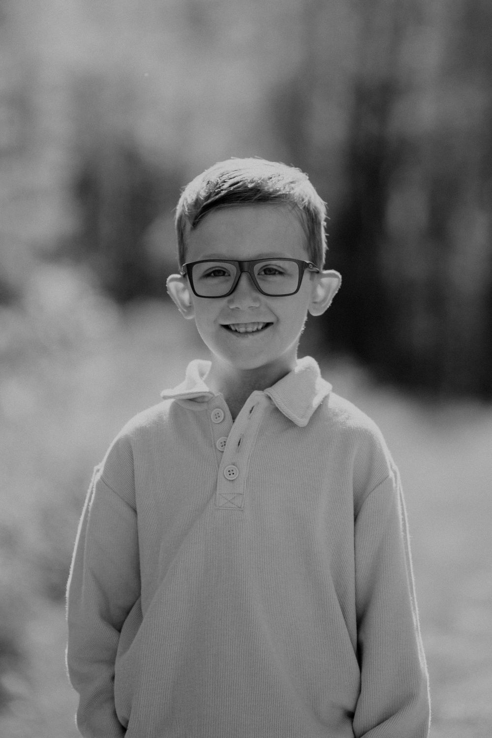 A series of five black and white portraits showing a young child in glasses and a polo shirt smiling in Stow, OH for family photo session