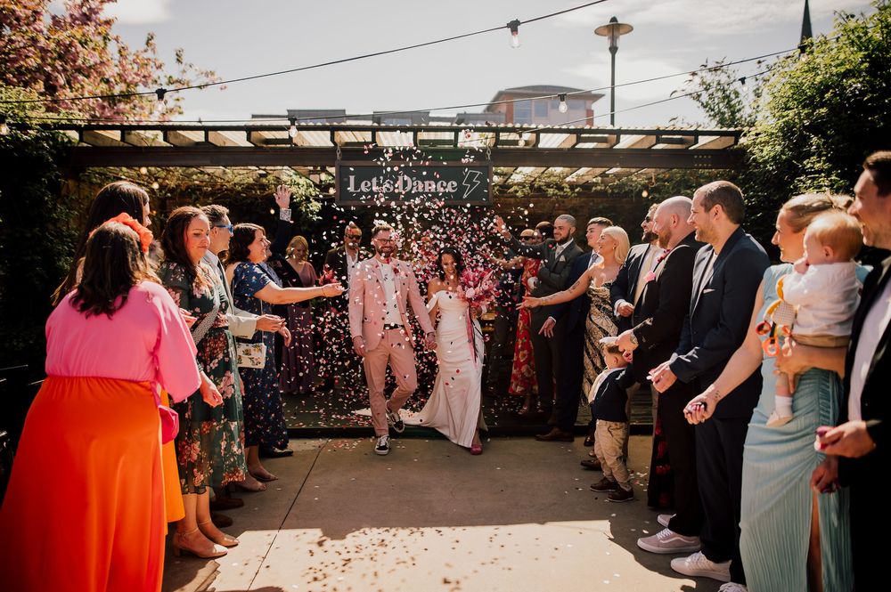 Wedding guests dance and celebrate together on an outdoor patio during a lively reception party.