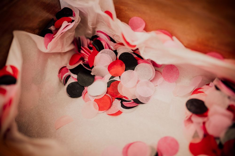 Pink and black paper hearts scattered on a white surface create a romantic Valentine's Day themed background.
