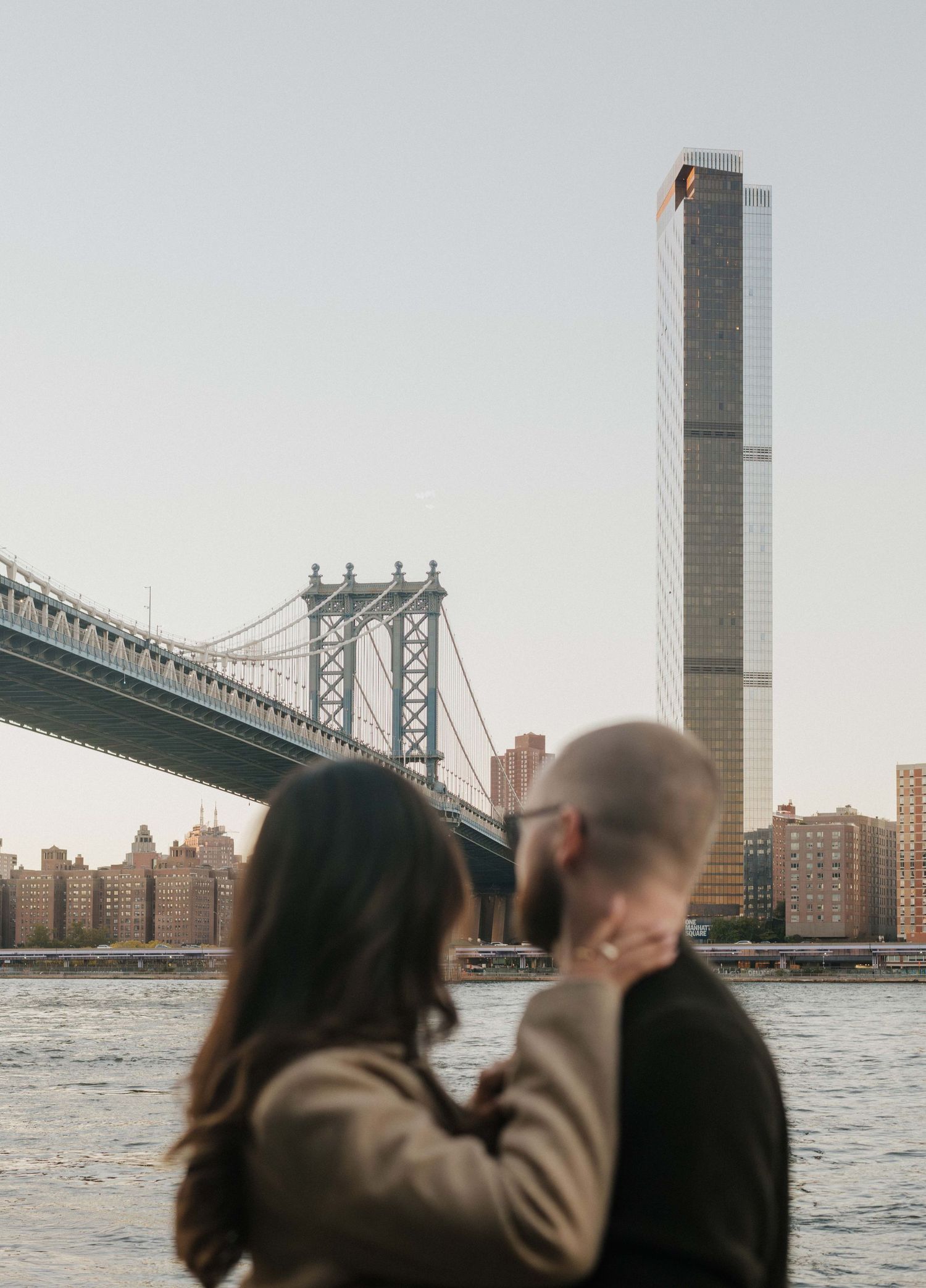 A couple sits romantically on stone steps in front of the Washington Square Arch in New York City during autumn.