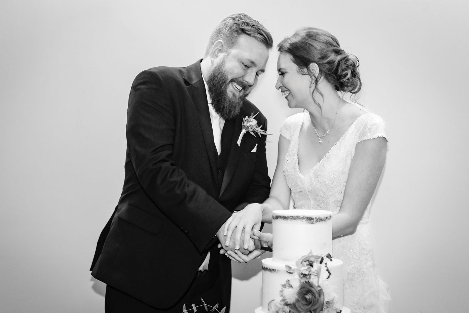 A joyful black and white wedding photo capturing a candid laughing moment between a bride and groom.