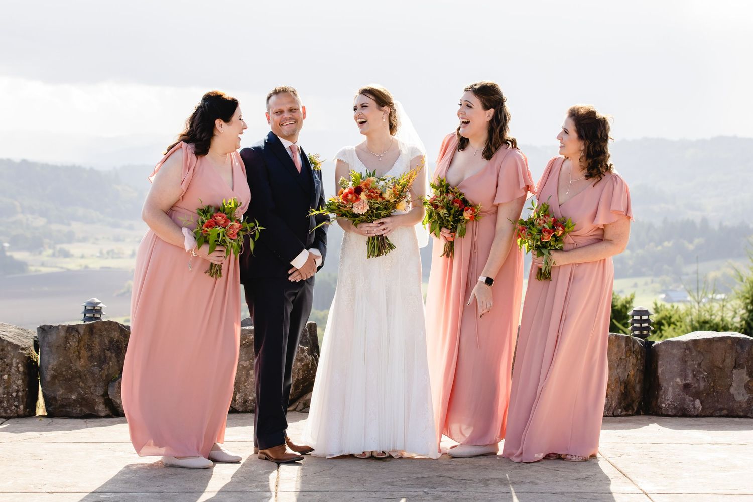 A wedding ceremony takes place on a scenic mountain overlook with rolling hills in the background.