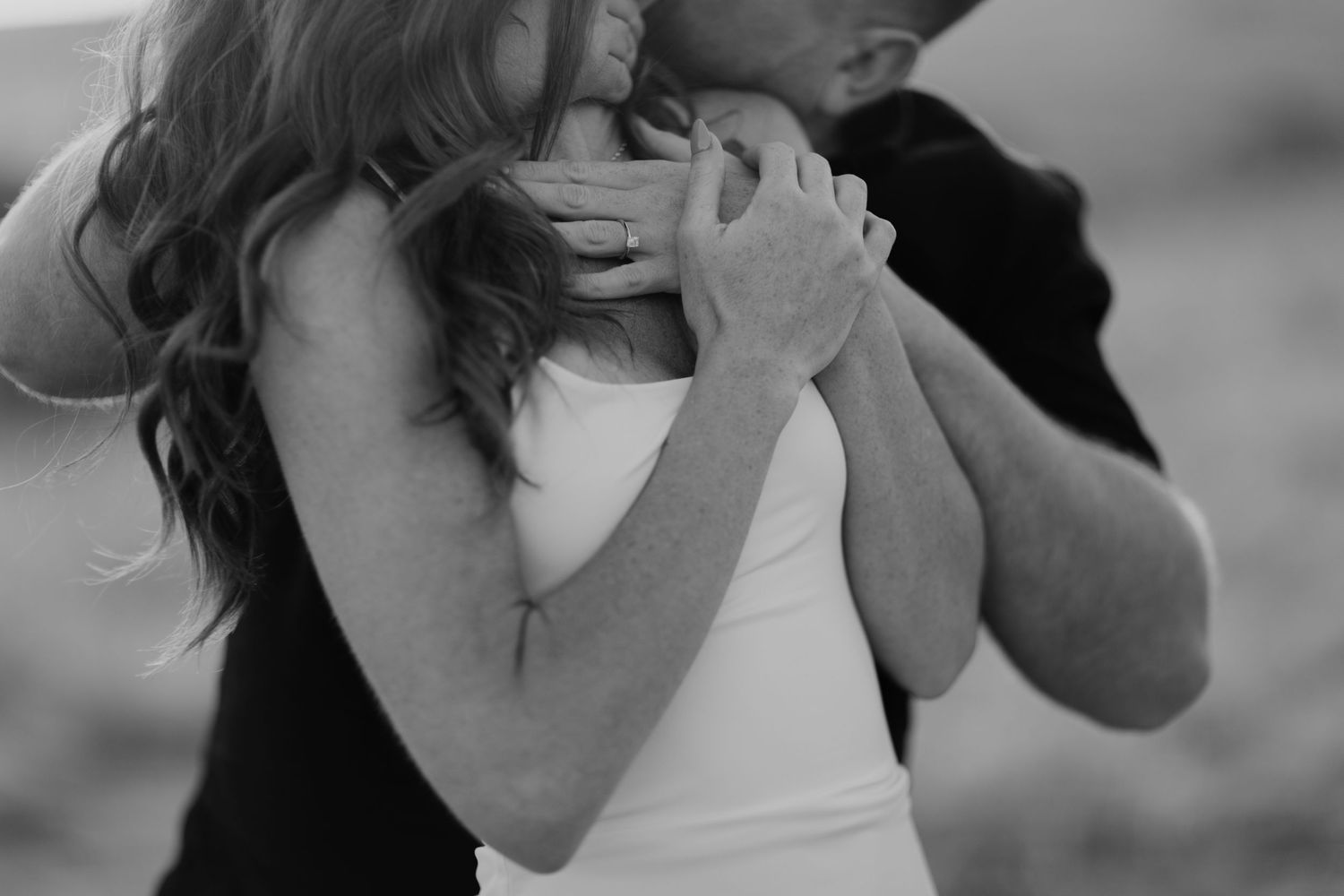 Intimate black and white portrait of a couple embracing in a tender moment.