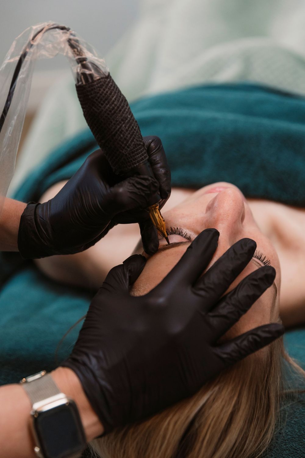 Close-up of hands wearing black gloves performing a cosmetic procedure.